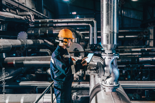 Portrait of young Caucasian man dressed in work wear using tablet while standing in heating plant.