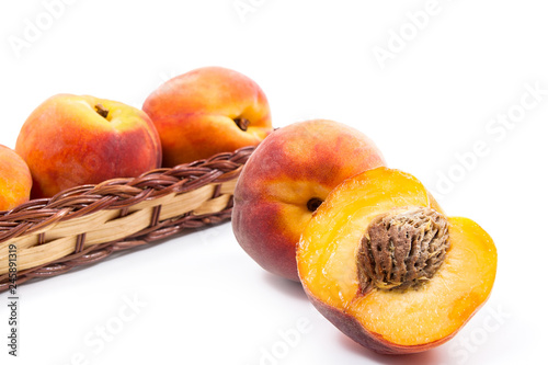 Whole and half of ripe peach fruit and several in basket isolated on white background. © kostik2photo