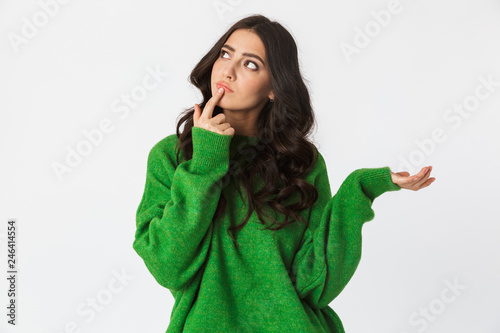 Beautiful thinking young woman dressed in green sweater posing isolated over white wall background. © Drobot Dean