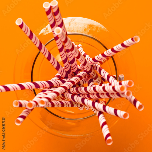 a glass with a paper straw on orange background the view from the top © Roman