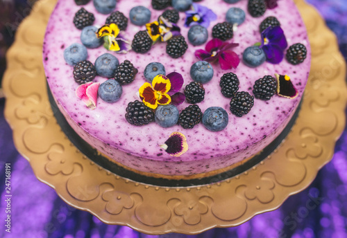 Festive cake with violet sour cream on a metal plate stand. © zzzdim