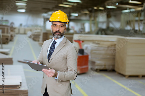 Middle-aged businessman with digital tablet in factory