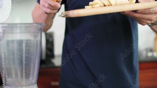 Close up of man hands cutting banana and then putting it into blender with knife © DragonImages