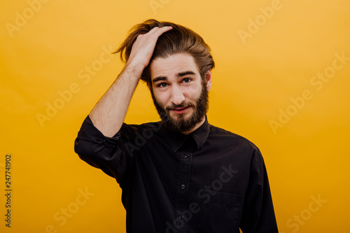 attractive man, with a hand in hair, on a yellow background, isolated © Alexandr