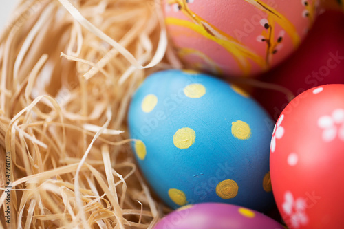 easter, holidays, tradition and object concept - close up of colored eggs in straw © Syda Productions