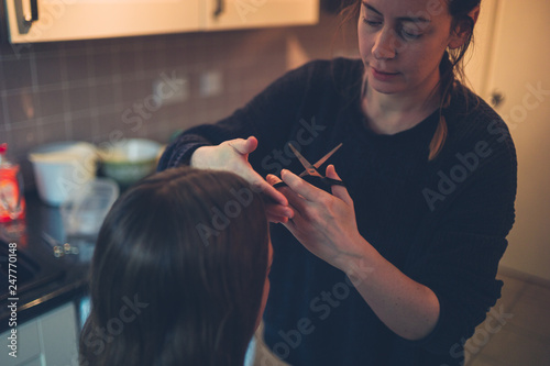 Woman cutting friend's hair in kitchen © LoloStock
