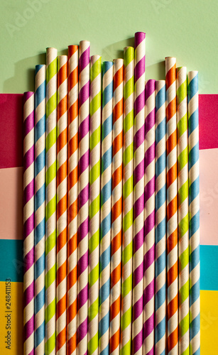 Colorful variegated drinking straws. Background of patterned straws and bright colour paper. Geometric backdrop. © Degimages