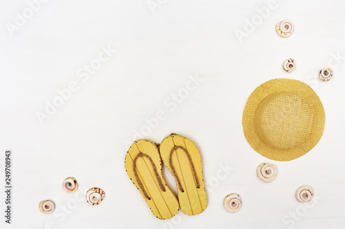 Straw hat and flip-flops on white background with copy space. Concept of beach holiday. © yrabota