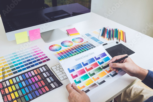 Image of male creative graphic designer working on color selection and drawing on graphics tablet at workplace with work tools and accessories © Freedomz