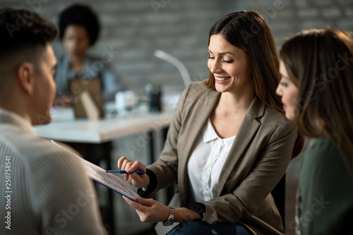 Happy insurance agent analyzing investment plans with her clients.