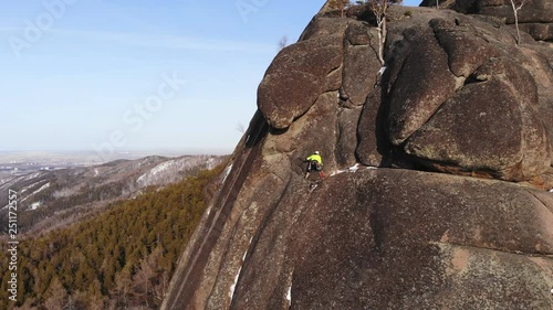 A brave man climbs to the top of the cliff. © mlinnikov