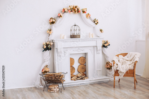 Interior with a beautiful decorative white fireplace and wood. Armchair by a decorative fireplace © Semenova Jenny