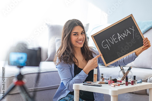 Young female blogger giveaway gift to fan following channel while recording vlog video with makeup cosmetic at home online influencer on social media concept. Live streaming viral