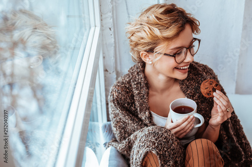 Positive cheerful woman holding a tasty cookie