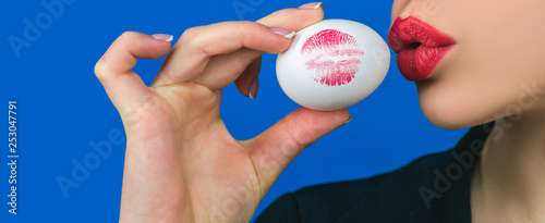 Happy easter banner. Red lip imprint on easter egg on blue background. Lipstick kiss print. Female mouth.