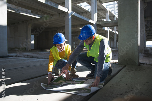 Male and female architects discussing over blueprint