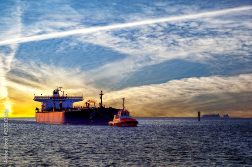 Beautiful sunset with a tug towing big tanker ship. © Nightman1965