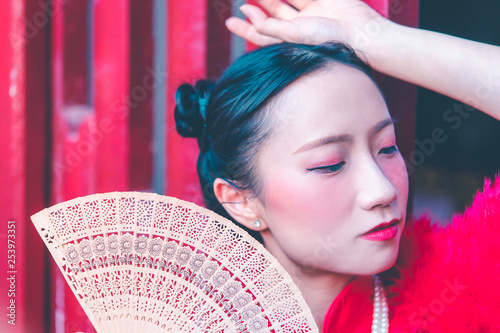 Young chinese woman with Fan on red background for chinese new year concept © junce11