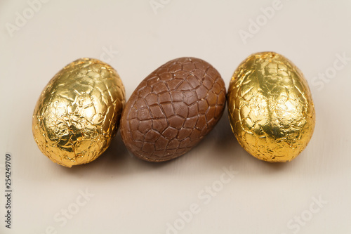Three milk chocolate eggs wrapped in golden paper for easter © oceane2508