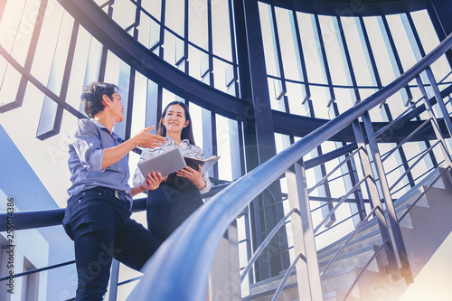Two business colleagues get discussion at stairway in modern office using tablet