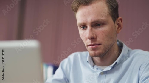Young man in a modern office, serious look man working on a laptop, workplace. © stockddvideo