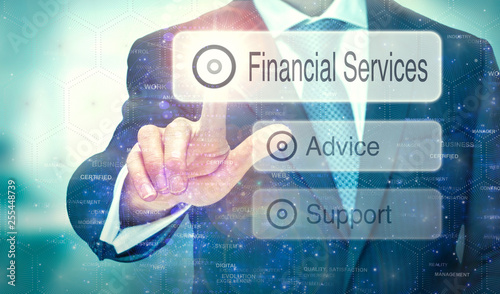 A business man selection a button on a futuristic display with aFinancial Services concept written on it.