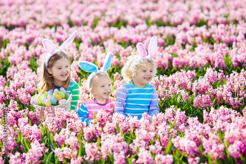 Kids on Easter egg hunt in blooming garden. © famveldman
