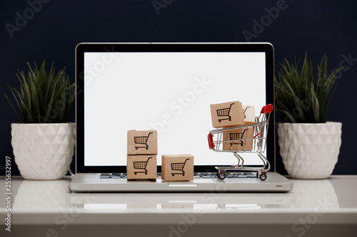paper boxes in a shopping cart on a laptop keyboard. Concepts about online shopping that consumers can buy things directly from their home or office just using a few clicks via web browser. © burdun