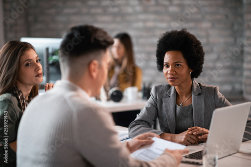 Smiling black insurance agent having a meeting with a couple in the office.