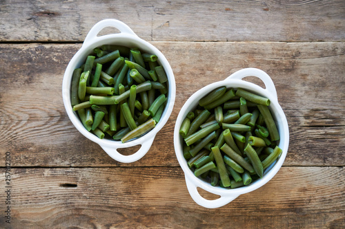 Boiled green beans in white bowls on wooden background © Юлия Коченкова