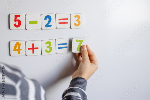 The boy solves mathematical examples. A child solves examples on a blackboard. © Maryna Osadcha