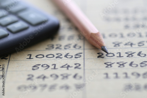 茶色の紙の上に書かれた数字の羅列と電卓と鉛筆 © Free1970