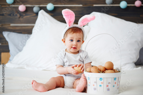 Portrait of adorable baby with bunny ears and easter basket © gpointstudio