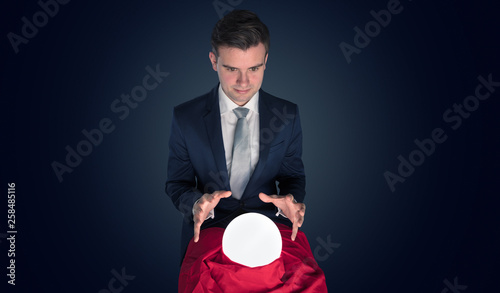 Handsome businessman with magic ball and copy space and dark background © ra2 studio