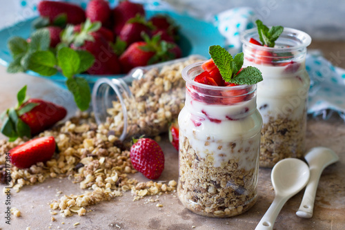 Homemade summer healthy breakfast. Greek yogurt with granola, pieces fresh strawberry on stone table.
