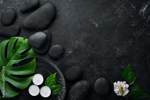 Zen stones and leaves with water drops. Spa background with spa accessories on a dark background. Top view. Free space for your text. © Yaruniv-Studio