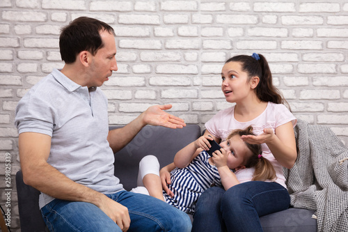 Parents Arguing At Home While Her Daughter Using Mobilephone © Andrey Popov