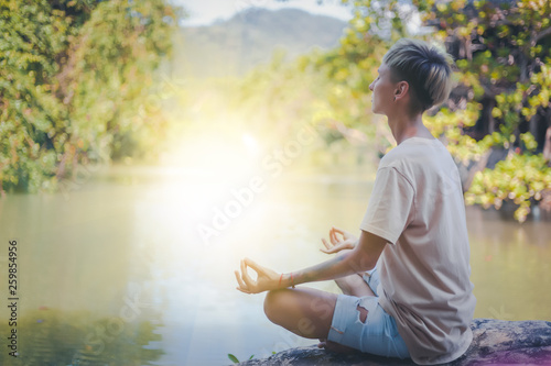 woman practices yoga and meditates in the lotus position, outdoor, lake in mountain © olezzo