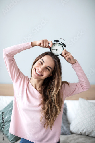 Joyful woman with alarm clock at home. © BestForYou