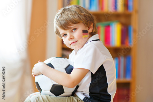 Little blond preschool kid boy with ball watching soccer football cup game on tv. Funny happy crying child fan having fun and cheering winning football team. Champions and world cup concept © Irina Schmidt