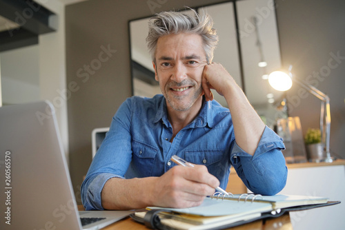 Mature man working from home smiling at camera © goodluz