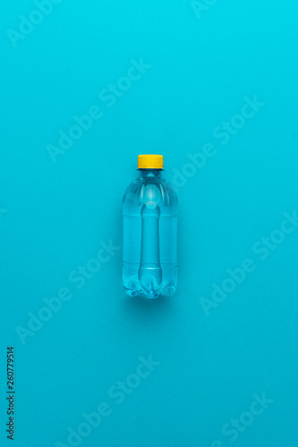 plastic water bottle with yellow cap on the blue background © Ruslan Grumble