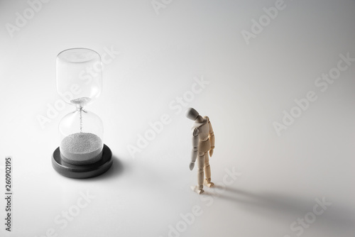 hourglass and wooden figure turing gray while color fading as time running out