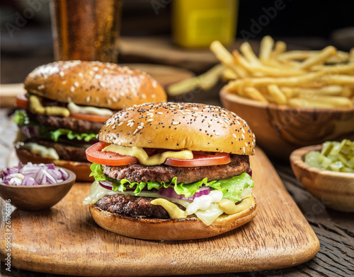 Hamburgers and French fries on the wooden tray. © volff