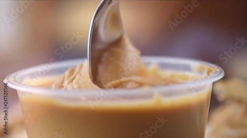 Peanut butter. Creamy smooth peanut butter in jar on a table. Spoon on Natural nutrition and organic food. American cuisine. 4K UHD video, slow motion © Subbotina Anna