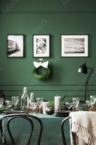 Wine glasses, candles and plates on table covered with green tablecloth © Photographee.eu