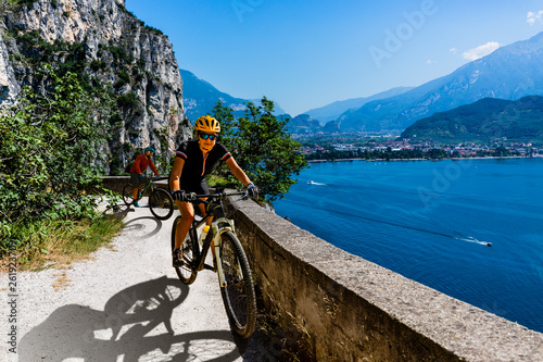 Cycling woman and man riding on bikes at sunrise mountains and Garda lake landscape. Couple cycling MTB enduro flow sentiero ponale trail track. Outdoor sport activity. © Gorilla