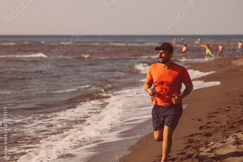 Young man jogging on the beach by the sea © djile