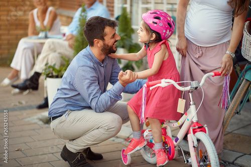 Young cheerful father buying new bicycle for little girl in bike shop . © luckybusiness
