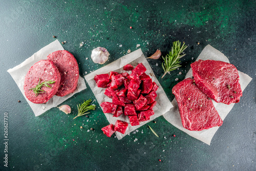 Various raw beef meat with spices and herbs, dark concrete background copy space © ricka_kinamoto